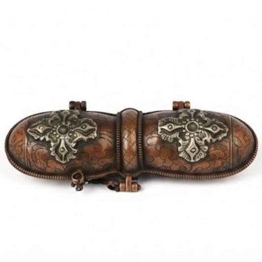 Estuche metálico ornamentado con relieves de flores y símbolos tradicionales nepalíes para protección de objetos rituales.