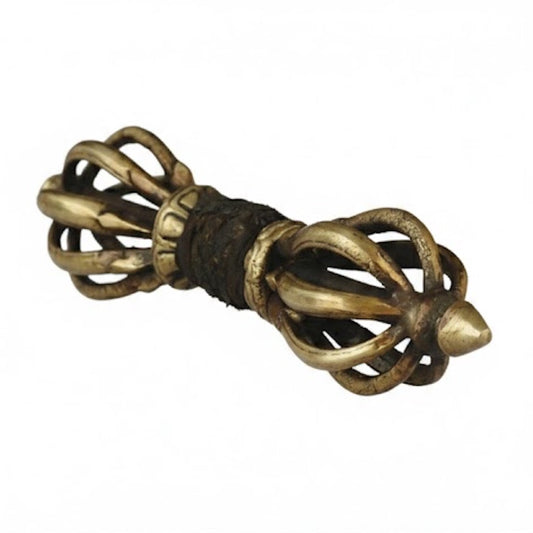 Vajra o Dorje ritual de bronce fabricado artesanalmente en Nepal con pátina antigua sobre fondo blanco.